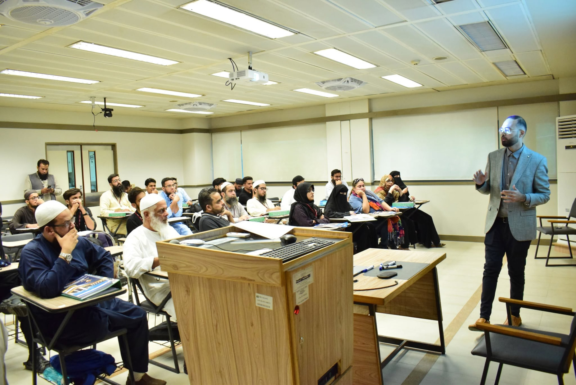 Basit conducting a workshop for a classroom audience